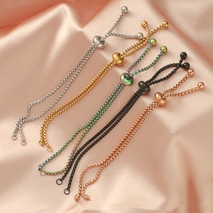 May include: Six adjustable bracelets with different colored chains and beads. The bracelets are made of silver, gold, black, and iridescent green.