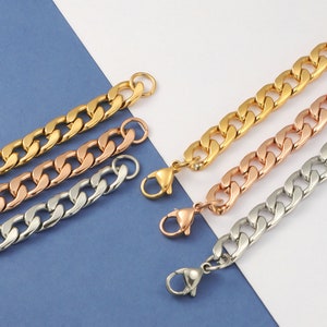Può includere: Tre collane a catena d'oro con chiusura a moschettone. Le catene sono di diverse larghezze e sono disposte in fila da sinistra a destra: oro, oro rosa e argento.