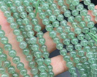 Könnte beinhalten: Eine Strähne grüner Aventurinperlen, jede Perle ist rund und hat eine durchscheinende, leicht trübe Optik. Die Perlen sind auf einem durchsichtigen Faden aufgereiht.
