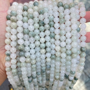 May include: A strand of white and green jade beads. The beads are round and smooth, and they have a subtle shimmer.