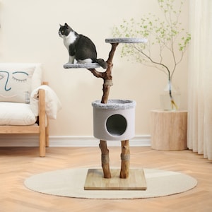 May include: A grey cat tree shaped like a tree trunk with a round platform, a small house, and a base. The cat tree is made of wood and has a rope-wrapped trunk. The cat tree is on a light grey rug.