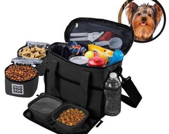 Könnte beinhalten: Schwarze Hundereise-Tasche mit mehreren Fächern, darunter zwei Futternäpfe, ein Wasserflaschenhalter und eine Reißverschlusstasche. Die Tasche ist gefüllt mit Hundefutter, Leckerlis, Spielzeug und anderem Zubehör. Die Tasche trägt den Schriftzug "Overland Dog Gear" auf der Vorderseite.