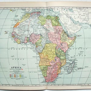 May include: A colourful, vintage map of Africa, displayed open. The map is divided into regions with different colours. The word "Africa" is printed at the bottom left. Measurements are not included.