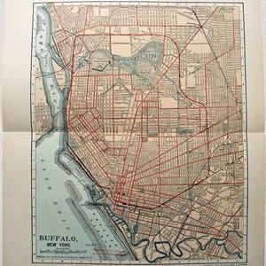 May include: Antique map of Buffalo, New York, featuring a detailed street grid in red over a beige background. The map includes the city's waterfront, parks, and the text "Buffalo, New York" at the bottom.