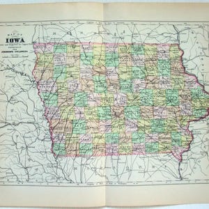 May include: A vintage map of Iowa, featuring a detailed depiction of the state's counties and geographical features. The map is printed on aged paper, with a title that reads "Map of Iowa". The map is divided into colorful sections, with a pink border.