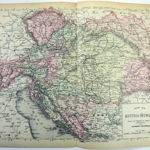 May include: Antique map of Austria-Hungary, featuring detailed geographical information. The map is printed on aged paper, with areas highlighted in pink and green. The title "Map of Austria-Hungary" is visible.