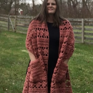 Puede incluir: Un chal de ganchillo con flecos y bolsillos de color rosa polvoriento.