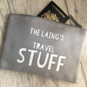 May include: Grey zipped pouch with the text "The Laing's Travel Stuff" printed in white. A British passport is partially visible inside the pouch.