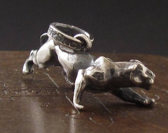 May include: A silver charm in the shape of a leaping panther. The charm has a textured surface and a ring at the top for attaching to a bracelet or necklace.