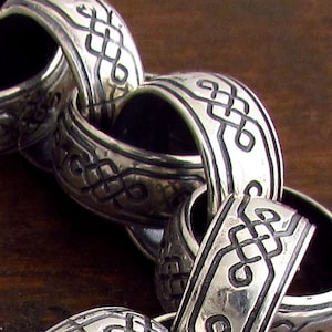 May include: A silver chain bracelet with intricate knot designs. Each link is a separate knot, creating a unique and textured look.