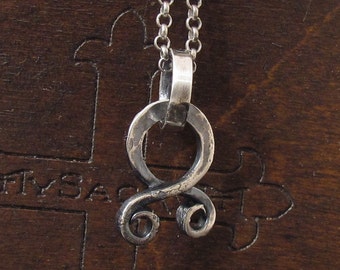 May include: Silver pendant necklace with a stylized knot design. The pendant is made of a thick, textured metal and has a simple, elegant look.