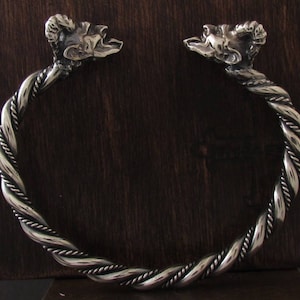 May include: Silver bracelet with a twisted rope design and ram's head accents.