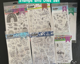 May include: A set of clear rubber stamps with various designs, including flowers, rainbows, mermaids, and beach scenes. The stamps are packaged in clear plastic bags with colorful borders and the number of pieces included in each set. The text "Stamps and Dies Set" is printed in green at the top of the image.