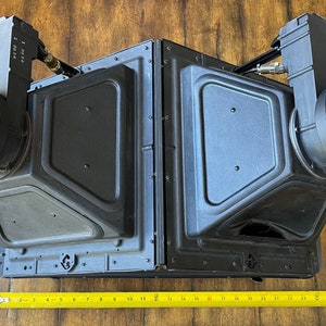 May include: Two black, rectangular, angled, audio speakers with round, black, circular, magnetic, speaker covers. The speakers are connected by a black metal frame. A yellow measuring tape is placed below the speakers.