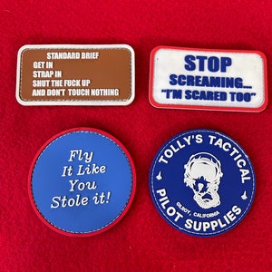 May include: Four embroidered patches with different designs and text. The first patch is brown with white text that reads "STANDARD BRIEF GET IN STRAP IN SHUT THE FUCK UP AND DON'T TOUCH NOTHING". The second patch is white with red and blue text that reads "STOP SCREAMING... "I'M SCARED TOO"". The third patch is blue with red stitching and white text that reads "Fly It Like You Stole it!". The fourth patch is blue with white stitching and white text that reads "TOLLY'S TACTICAL PILOT SUPPLIES GILROY, CALIFORNIA".