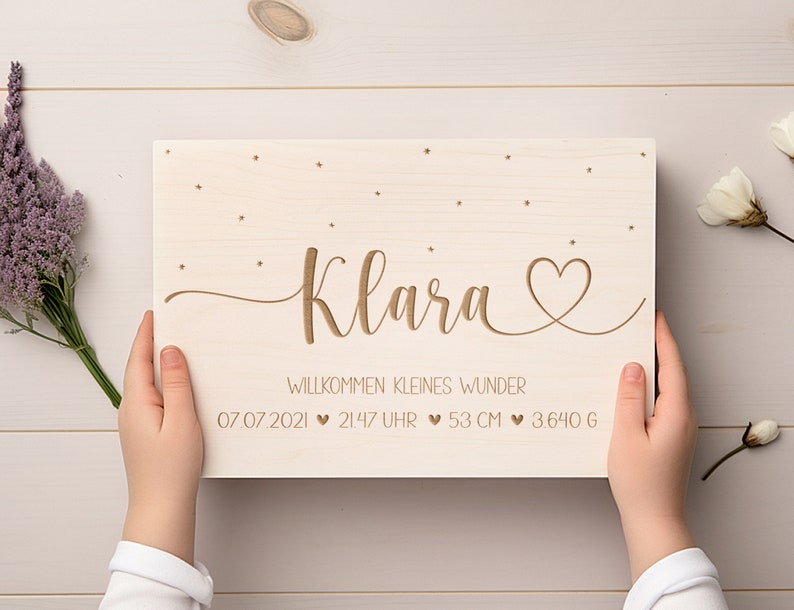 May include: A wooden sign with the name Klara engraved in cursive script, surrounded by small stars. The sign also includes the text "Willkommen kleines Wunder" and the date 07 07 2021, time 21:47 Uhr, weight 3.640 g, and length 53 cm.