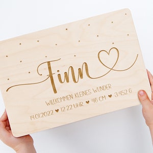 May include: A wooden plaque with the name "Finn" engraved in a cursive font. The plaque also includes the date "14.01.2022", time "12:22 Uhr", and the text "Willkommen kleines Wunder" along with a heart symbol. The plaque also includes the measurements "46 cm" and "3,452 g" with heart symbols.