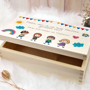 K&ouml;nnte beinhalten: Eine Holzkiste mit einem bunten Design auf dem Deckel. Das Design beinhaltet einen Regenbogen, eine Sonne, Wolken und Strichm&auml;nnchen von Kindern. Der Text auf dem Deckel lautet "Danke, dass du uns beim Wachsen geholfen hast! Deine Kita-Kinder aus F&uuml;nfhausen."