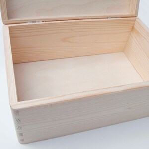 May include: An empty wooden box with a hinged lid. The box is made of light-colored wood and has a natural finish.