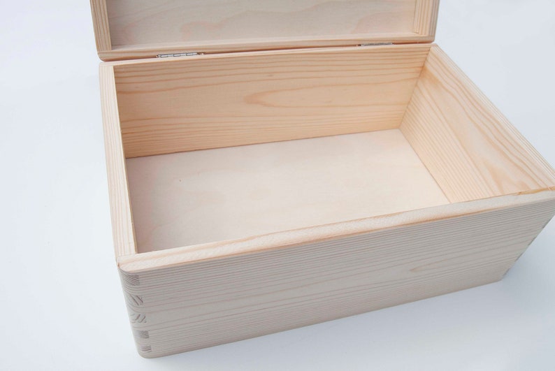 May include: An empty wooden box with a hinged lid. The box is made of light-colored wood and has a natural finish.