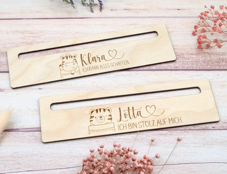 May include: Two wooden desk organizers with a rectangular shape and a cutout handle. Each organizer features a cartoon tiger illustration and personalized text: "Klara, I can do anything" and "Lotta, I am proud of myself."