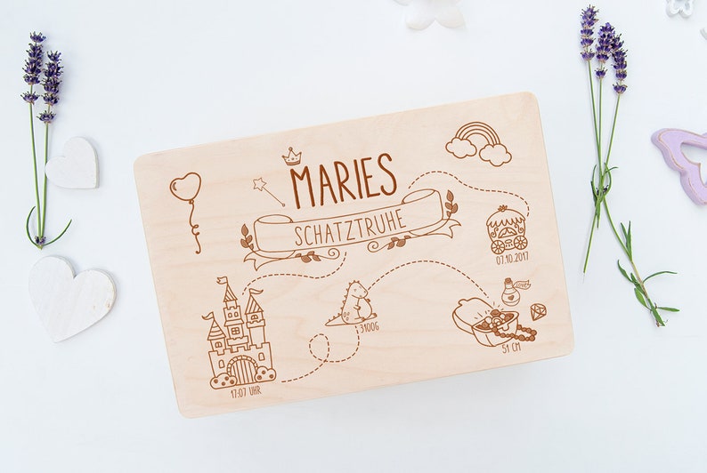 May include: A wooden treasure box with a personalized inscription "MARIES SCHATZTRUHE" and a whimsical illustration of a castle, a dinosaur, a carriage, and a treasure chest. The box is decorated with a crown, a rainbow, and stars.