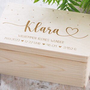 May include: A wooden keepsake box with a light wood finish. The lid is engraved with the name "Klara" and the text "Willkommen kleines Wunder 14.01.2022 &hearts; 12:22 Uhr &hearts; 46 cm &hearts; 3452 g".