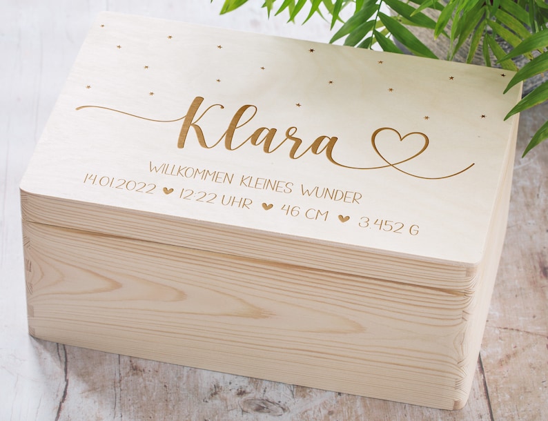 May include: A wooden keepsake box with a light wood finish. The lid is engraved with the name "Klara" and the text "Willkommen kleines Wunder 14.01.2022 &hearts; 12:22 Uhr &hearts; 46 cm &hearts; 3452 g".