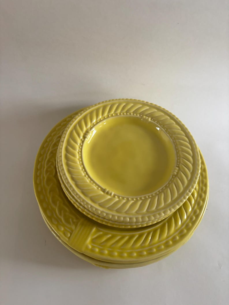 Puede incluir: Una pila de platos de cer&aacute;mica amarillos. Los platos tienen un dise&ntilde;o texturizado y en relieve alrededor de los bordes. Los platos son de diferentes tama&ntilde;os, con un plato m&aacute;s peque&ntilde;o apilado encima de platos m&aacute;s grandes. Los platos son de color amarillo brillante.