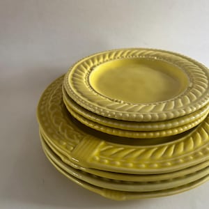 Puede incluir: Una pila de platos de cer&aacute;mica amarillos. Los platos tienen un dise&ntilde;o texturizado y en relieve en los bordes. Los platos son de diferentes tama&ntilde;os, con un plato m&aacute;s peque&ntilde;o encima de una pila de platos m&aacute;s grandes. Los platos son de color amarillo brillante.