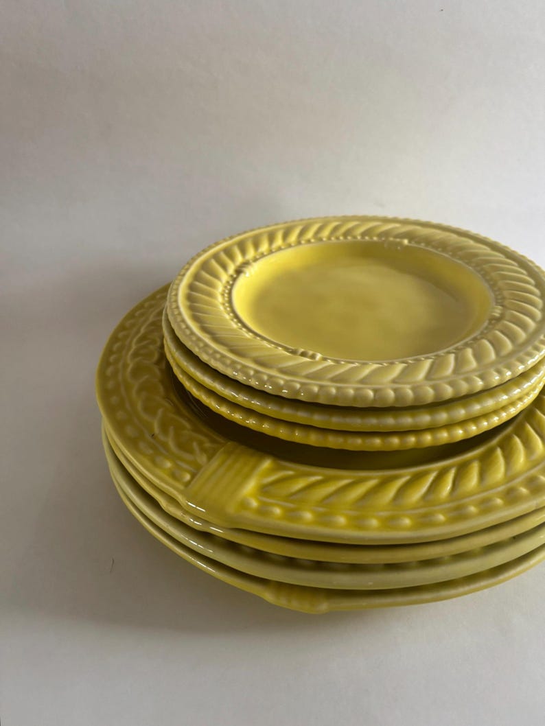 Puede incluir: Una pila de platos de cer&aacute;mica amarillos. Los platos tienen un dise&ntilde;o texturizado y en relieve en los bordes. Los platos son de diferentes tama&ntilde;os, con un plato m&aacute;s peque&ntilde;o encima de una pila de platos m&aacute;s grandes. Los platos son de color amarillo brillante.