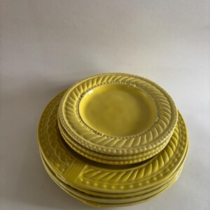 Puede incluir: Una pila de platos de cer&aacute;mica amarillos con un dise&ntilde;o texturizado y en relieve alrededor de los bordes. Los platos est&aacute;n apilados uno encima del otro, mostrando los patrones detallados y el color brillante y soleado. Los platos son probablemente para cenar.