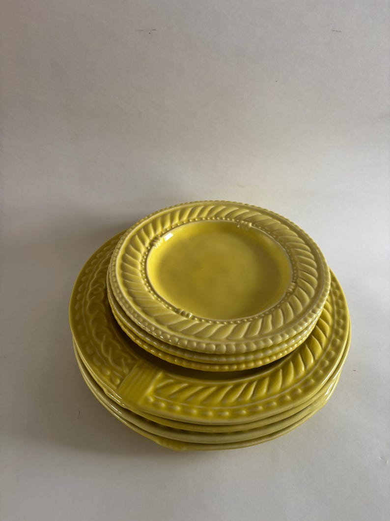 Puede incluir: Una pila de platos de cer&aacute;mica amarillos con un dise&ntilde;o texturizado y en relieve alrededor de los bordes. Los platos est&aacute;n apilados uno encima del otro, mostrando los patrones detallados y el color brillante y soleado. Los platos son probablemente para cenar.