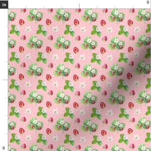 Peut inclure: Un tissu rose avec un motif répété de fleurs blanches et de fraises rouges. Le fond est rose clair avec de petits points blancs.