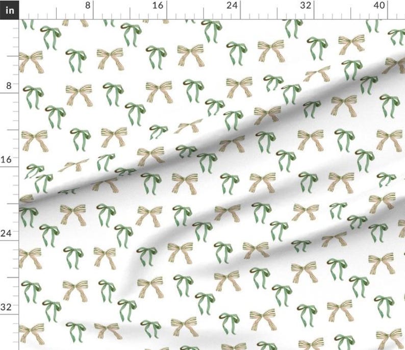 Pu&ograve; includere: Un tessuto bianco con un motivo ripetitivo di fiocchi verdi e beige. I fiocchi sono disposti a scacchiera.