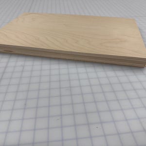Puede incluir: Una pila de finas l&aacute;minas de madera clara, probablemente contrachapado, con un acabado de veta de madera natural.