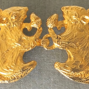 Puede incluir: Un par de hebillas de cinturón de metal dorado en forma de ardilla. Cada hebilla presenta un diseño de ardilla detallado con una cola enroscada.