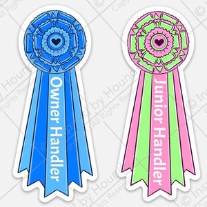 Peut inclure: Deux rosettes bleues et roses avec des rubans blancs. La rosette bleue porte l'inscription "Owner Handler" sur le ruban. La rosette rose porte l'inscription "Junior Handler" sur le ruban.