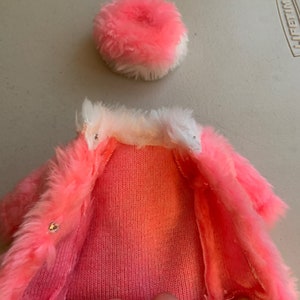 May include: A pink faux fur coat with a white faux fur collar and a matching pink faux fur hat.