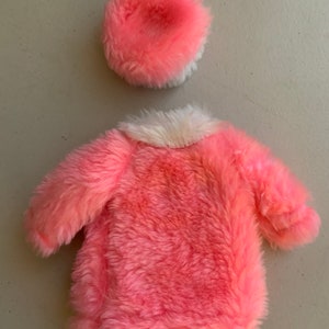 May include: A pink faux fur coat with a white faux fur collar and a matching pink faux fur hat.