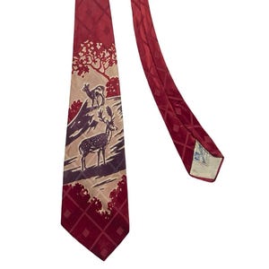 May include: A burgundy tie with a diamond pattern and a landscape scene featuring deer. The tie has a detailed illustration of deer in a natural setting, with a tree and a light tan background.