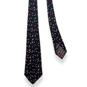 May include: A black tie with a repeating pattern of small red and white squares. The tie is angled, showing the full length and the detailed pattern. The tie's end has a patterned design.