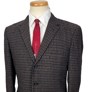 May include: A brown and black patterned blazer with a red tie and white collared shirt. The blazer has a three-button closure and two front pockets. The tie has a white and red design.