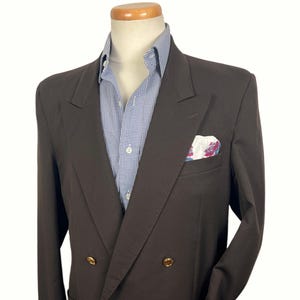 May include: A dark brown double-breasted blazer with gold buttons, a blue and white checkered shirt, and a floral pocket square. The blazer is displayed on a mannequin.