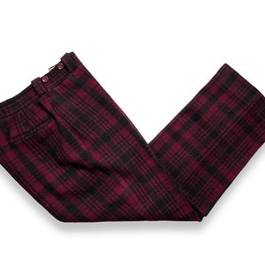 May include: Red and black plaid pants with a button closure. The pants are made of a soft, woven fabric.