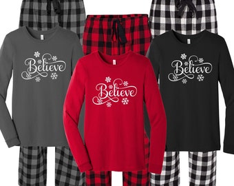 May include: Three sets of matching pajamas with a red, black, and gray plaid pattern. Each set includes a long-sleeved shirt with the word "Believe" in a white cursive font with snowflakes.