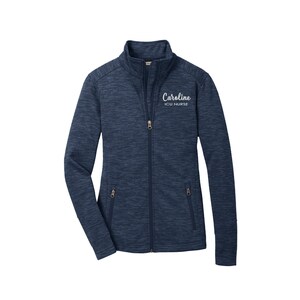 May include: A navy blue zip-up jacket with a heather pattern. The jacket has a white embroidered name "Caroline" and the text "ICU Nurse".