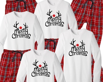 May include: White long-sleeved pajamas with red and black plaid pants. The shirts feature a reindeer with antlers and a red nose and the text "merry christmas".