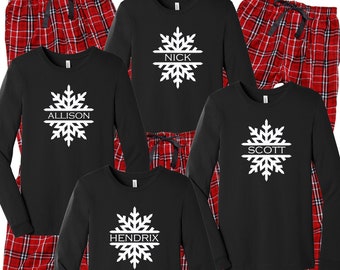 May include: A set of four black long-sleeved shirts with a white snowflake design and a name printed across the snowflake. The shirts are paired with red and black plaid pajama pants.
