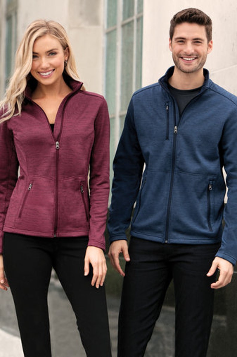 May include: Two people wearing zippered jackets. The person on the left is wearing a burgundy jacket and the person on the right is wearing a navy blue jacket.